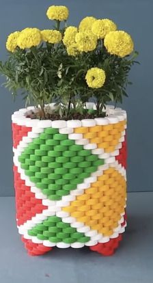 a planter made out of legos with yellow flowers in it