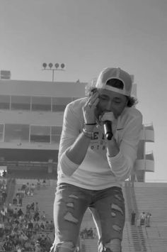 a man standing on top of a skateboard in front of a stadium filled with people