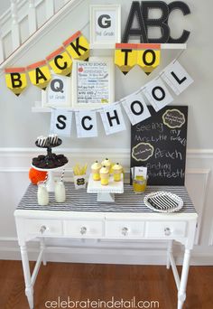 a white table topped with cupcakes and cakes next to a wall covered in letters