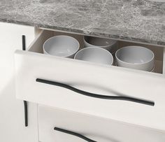 an open drawer in a kitchen with bowls and utensils on the bottom shelf