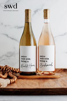 two bottles of wine sitting on top of a wooden cutting board next to some nuts