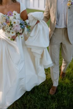 the bride and groom are walking through the grass