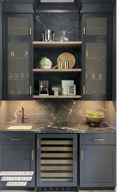 a kitchen with black cabinets and marble counter tops, gold trimmings on the doors