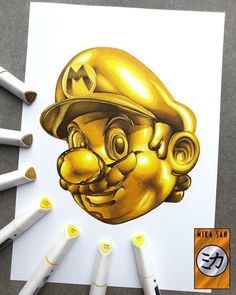 a drawing of a gold mario bros character on white paper next to markers and pens