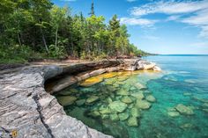 the water is crystal blue and clear with rocks in it's foreground, surrounded by trees