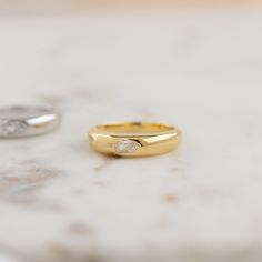 two wedding rings sitting on top of a marble table next to each other, one with a diamond in the middle