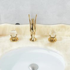 a bathroom sink with two golden faucets next to it's white marble counter top