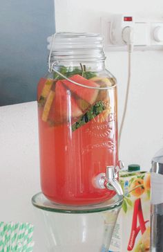 a mason jar filled with watermelon and strawberries sitting on a kitchen counter