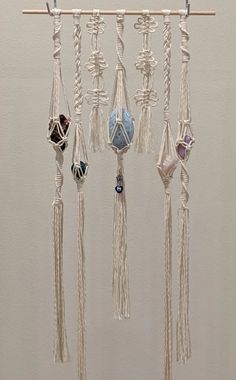 a white wall hanging with various beads and tassels on it's sides