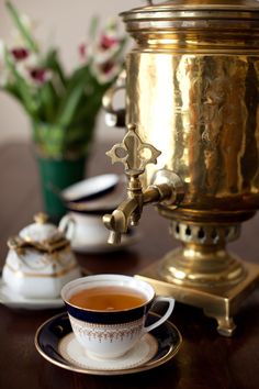 there is a cup of tea on the table next to some cups and saucers