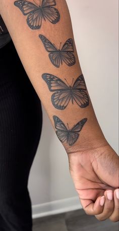 a woman's arm with three butterflies on it and one is holding the other hand