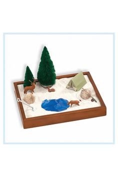 a wooden tray with some fake trees and rocks on it, in front of a white background