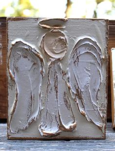 an angel is carved into the side of a wooden block with white paint on it