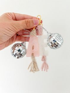 a person is holding some small ornaments in their hand and it looks like they are hanging from the ceiling