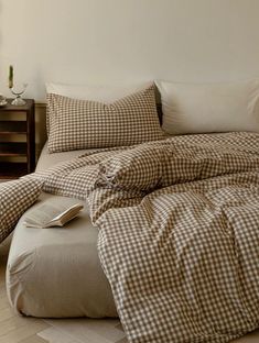 a bed with brown and white checkered comforter next to a night stand on the floor