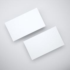 two white business cards sitting next to each other on top of a gray surface,