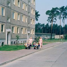 an older couple walking down the street with their child's toy cars