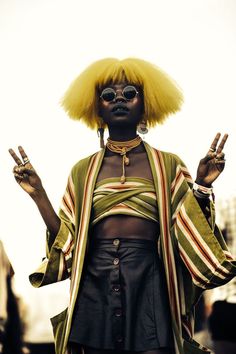 a woman with yellow hair and glasses on her head is standing in front of the camera