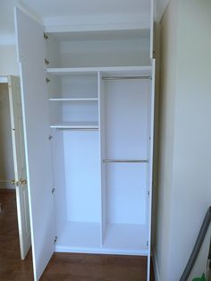 an empty closet with white walls and wooden floors