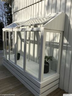 a small white house with glass windows and a potted plant in the window sill