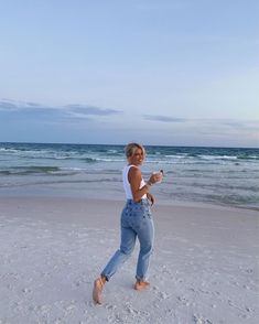 a woman is running on the beach with a frisbee in her hand and smiling