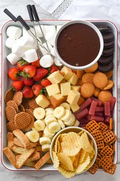 a platter filled with crackers, strawberries, cheese and other snacks next to dipping sauce