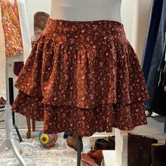 This Adorable Skirt Features Two Layers Of Tiered, Corduroy Floral, And Elastic Smocking In The Back For A Great Flexible Fit Non-stretch Cotton Skirt With Floral Print, Non-stretch Brown Cotton Skirt, Cotton Mini Skirt For Fall, Fall Cotton Mini Skirt, Non-stretch Cotton Skirt For Fall, Casual Lined Skort For Fall, Brown Cotton Skirt For Fall, Casual Non-stretch Skort For Fall, Cotton Lined Mini Skirt For Fall