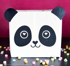 a paper bag with a panda face painted on it and lots of candy scattered around