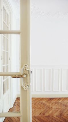 an open door in a white room with wood floors