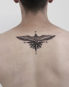 the back of a man's neck with a compass tattoo on his left side