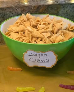 a green bowl filled with cheetos sitting on top of a counter next to candy