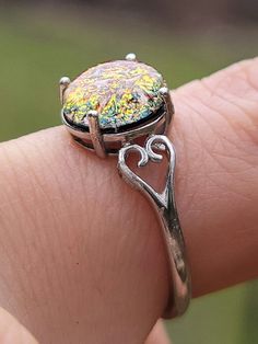 a close up of a person's hand holding a ring with a stone on it