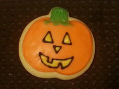 a decorated halloween cookie with a jack - o'- lantern face