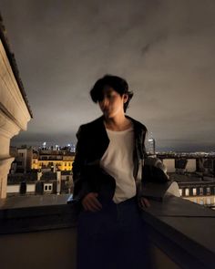 a woman standing on top of a roof next to a tall building