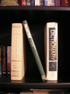 three books are sitting on a shelf in front of the bookshelf with several other books