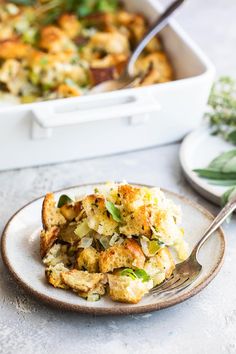 a white plate topped with stuffing next to a casserole dish filled with vegetables