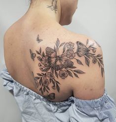 the back of a woman's shoulder with flowers and butterflies on it