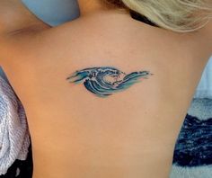 a woman's back with a wave tattoo on her left side ribcage