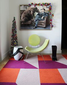 a living room decorated for christmas with colorful rugs and art on the wall above