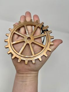 a hand holding a wooden gear wheel in it's palm