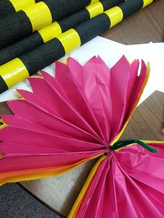 a pink flower sitting on top of a table next to some black and yellow poles