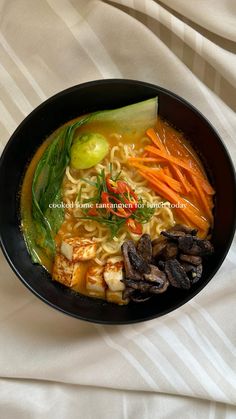 a black bowl filled with noodles and vegetables