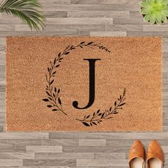 a door mat with the letter j on it and a pair of shoes next to it