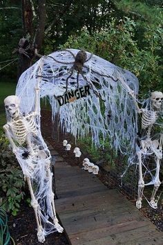 two skeleton statues in front of a fence with the word danger written on it