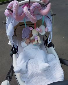 a baby is in a stroller with stuffed animals hanging from it's hooks