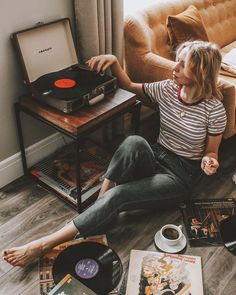 a woman sitting on the floor next to a record player