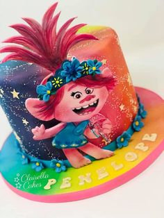 there is a birthday cake that looks like a troll on top of a rainbow hat