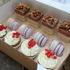 an open box filled with cupcakes covered in white frosting and topped with cherries