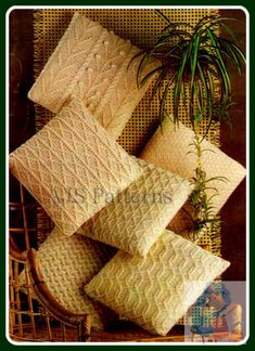 four white knitted pillows sitting on top of a chair next to a potted plant