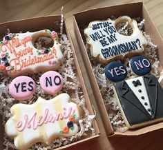 two decorated cookies in a box on top of a wooden table next to each other